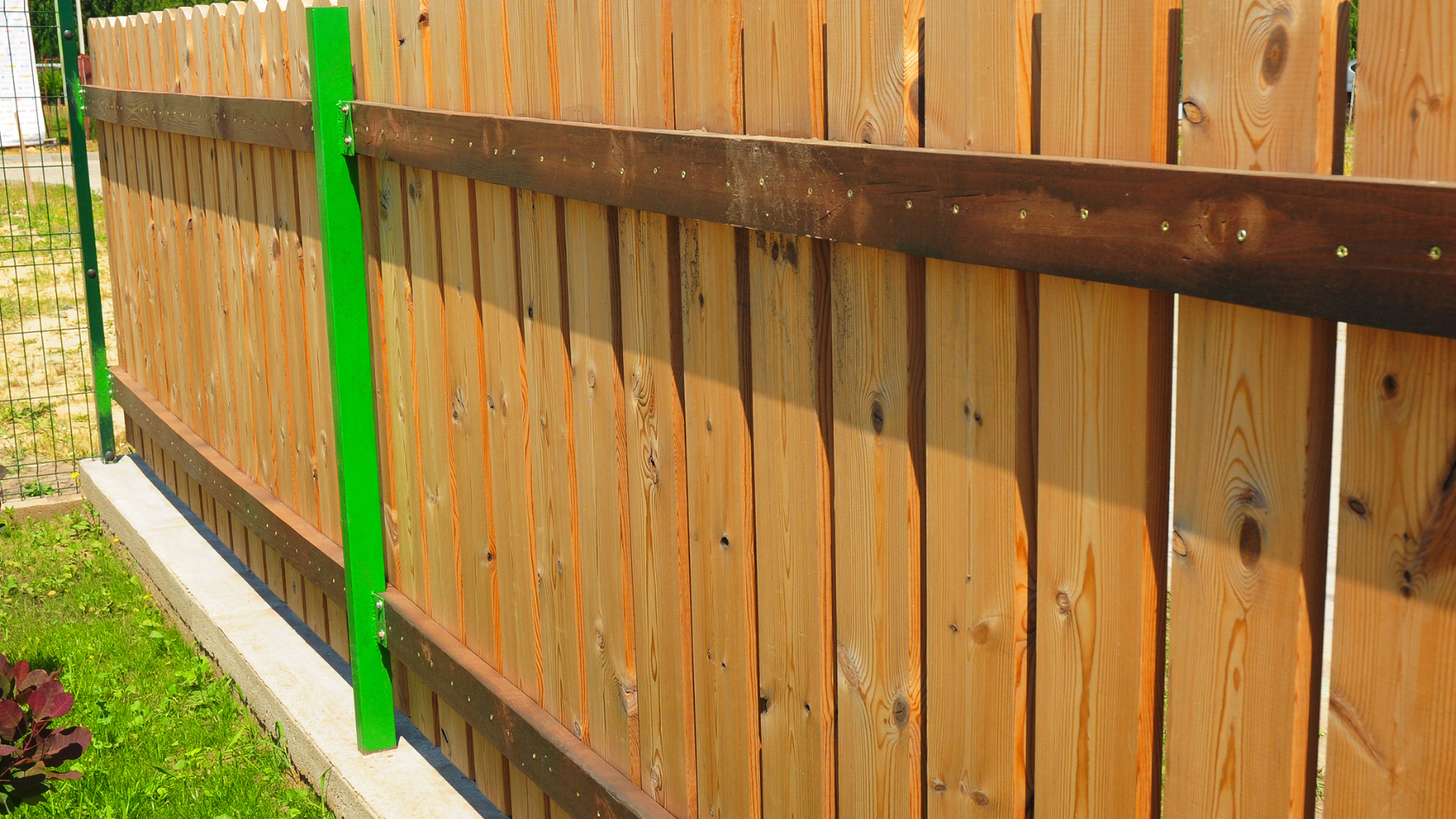 A wooden fence with a green post on it