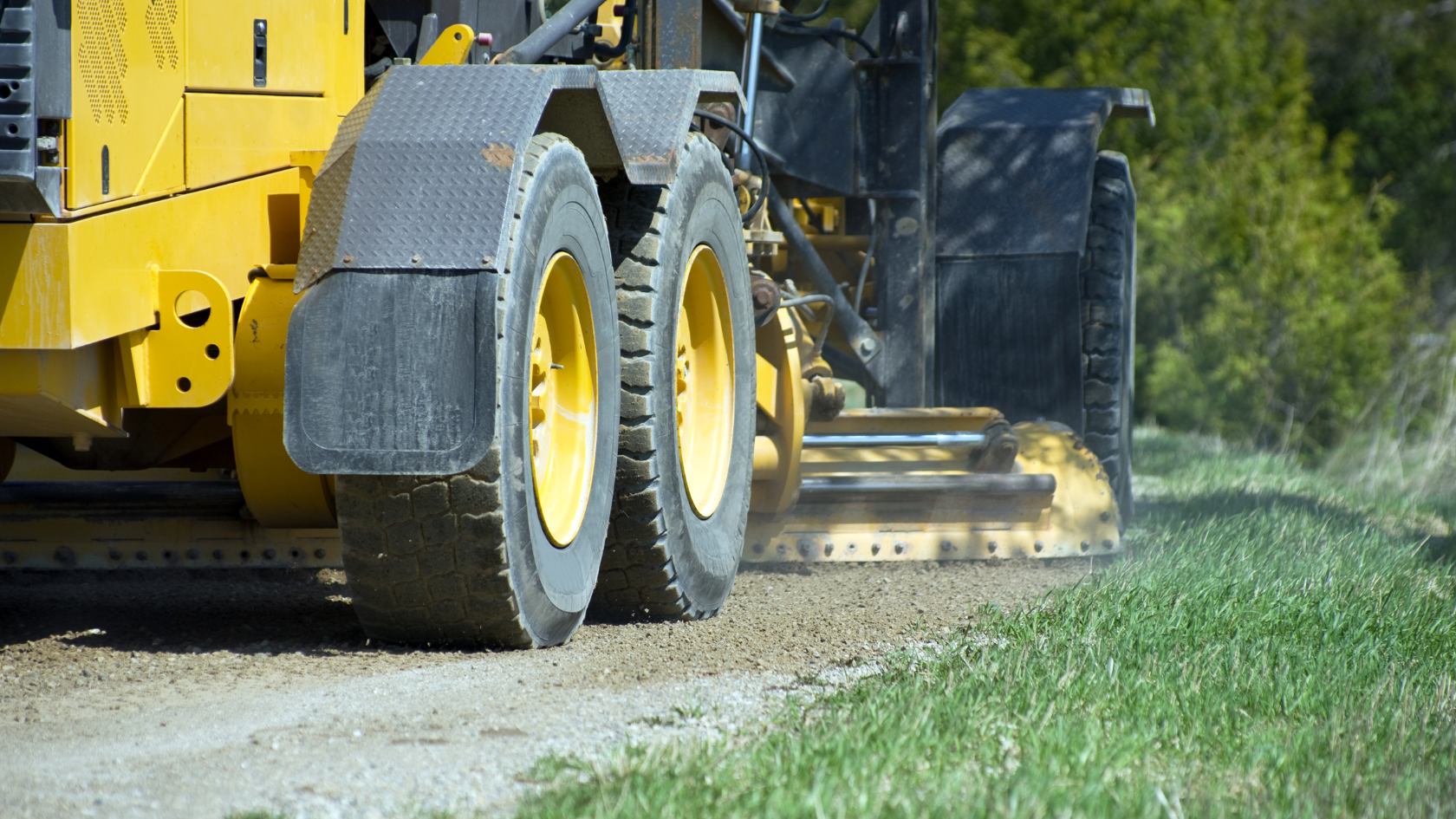 A yellow tractor is driving down a dirt road